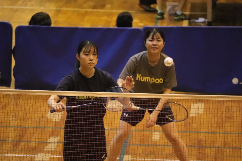 バドミントン部の練習風景：ラケットを持ちシャトルを打つ生徒たち