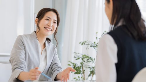 机を挟んで向かい合い、話をする2人